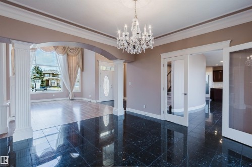 Foyer featuring high-gloss dark tile flooring, a crystal chandelier, and a decorative ceiling medallion - 2408 Tegler Green, Edmonton, AB - Indoor Photo Showing Other Room