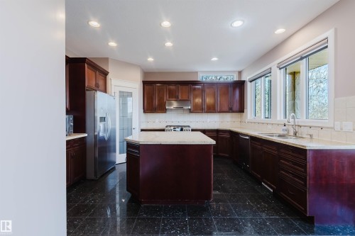 Kitchen featuring dark wood cabinetry, a central island with a light-toned countertop, and recessed ceiling lighting - 2408 Tegler Green, Edmonton, AB - Indoor Photo Showing Kitchen With Double Sink With Upgraded Kitchen