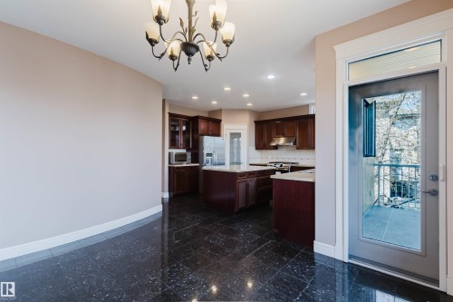 Spacious kitchen area featuring dark wood cabinetry, light-toned countertops, and stainless steel appliances - 2408 Tegler Green, Edmonton, AB - Indoor