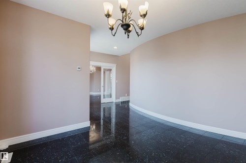Entry area featuring dark, reflective flooring, a curved wall, and a decorative chandelier - 2408 Tegler Green, Edmonton, AB - Indoor Photo Showing Other Room