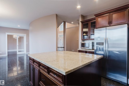 Kitchen island with a light-toned stone countertop and dark wood cabinetry - 2408 Tegler Green, Edmonton, AB - Indoor Photo Showing Kitchen