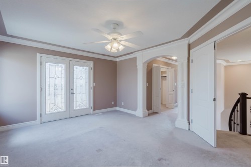 Interior space featuring light-toned carpeting, decorative glass French doors, crown molding, a tray ceiling, and a ceiling fan - 2408 Tegler Green, Edmonton, AB - Indoor Photo Showing Other Room