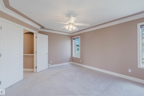 Spacious room featuring light-toned carpeting, two windows with blinds, a ceiling fan with integrated lighting, and crown molding - 2408 Tegler Green, Edmonton, AB - Indoor Photo Showing Other Room