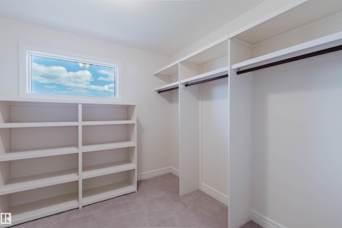 Spacious closet featuring extensive built-in shelving, multiple hanging rods, and a large horizontal window - 2408 Tegler Green, Edmonton, AB - Indoor With Storage
