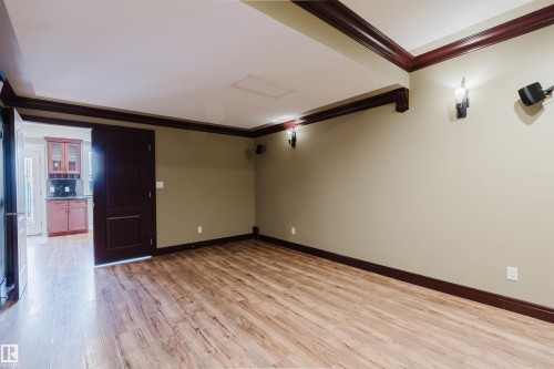 Spacious room featuring wood-finish flooring, light green walls, and dark wood trim - 2408 Tegler Green, Edmonton, AB - Indoor Photo Showing Other Room