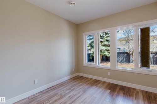 Neutral painted walls with white trim, wood-finish flooring, and a large window bank - 2408 Tegler Green, Edmonton, AB - Indoor Photo Showing Other Room