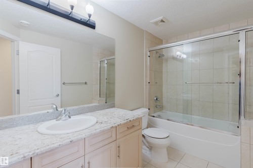 Bathroom featuring a light-toned vanity with an integrated sink, a tiled backsplash, and a large wall-mounted mirror with overhead lighting - 2408 Tegler Green, Edmonton, AB - Indoor Photo Showing Bathroom