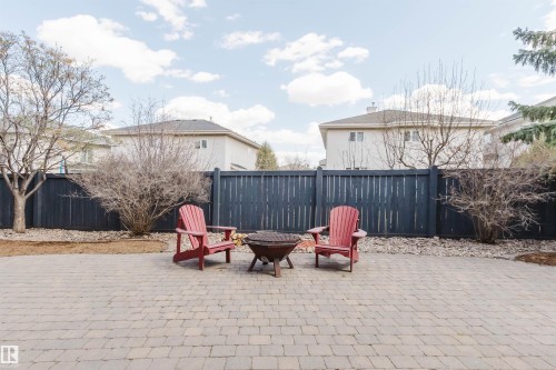 Spacious paver patio with a central fire pit, bordered by a dark-stained privacy fence - 2408 Tegler Green, Edmonton, AB - Outdoor