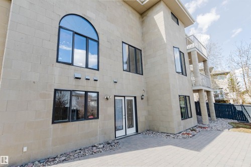 Stone block exterior featuring multiple windows with black trim, including a prominent arched window on the upper level - 2408 Tegler Green, Edmonton, AB - Outdoor With Exterior