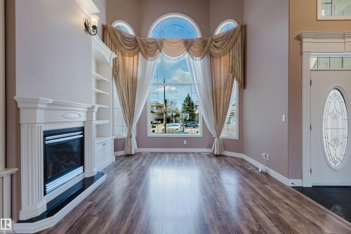 Vaulted living space with expansive arched windows and wood-finish flooring - 2408 Tegler Green, Edmonton, AB - Indoor With Fireplace
