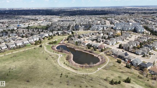 Residential area featuring a pond with surrounding walking paths, mature trees, and a variety of detached homes and multi-family buildings - 2408 Tegler Green, Edmonton, AB - Outdoor With View