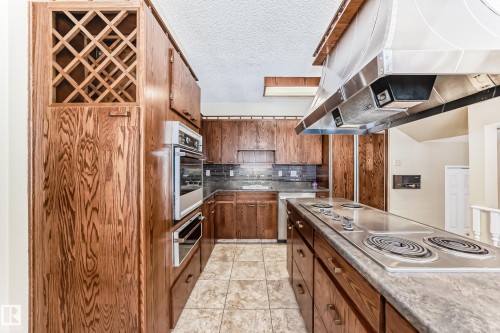 Oak Hanover cabinets, wine area and a double turn pantry door. Cook top allows for rotisserie cooking and  barbecue. Equipment is in the drawers. - 38 Lancaster Crescent, St. Albert, AB - Indoor Photo Showing Kitchen