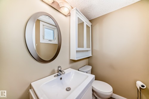 Half bath off the back door. Sink, toilet and wall cabinet and mirror. Window faces the side yard. - 38 Lancaster Crescent, St. Albert, AB - Indoor Photo Showing Bathroom