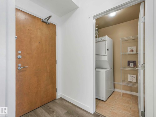 Entryway featuring wood-finish flooring and a laundry closet with stacked appliances, tile flooring, and wire shelving - 305 10504 99 Avenue, Edmonton, AB - Indoor Photo Showing Laundry Room