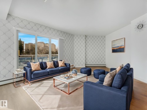 Expansive living area featuring a large window, patterned accent walls, wood-finish flooring, and a white ceiling - 305 10504 99 Avenue, Edmonton, AB - Indoor Photo Showing Living Room