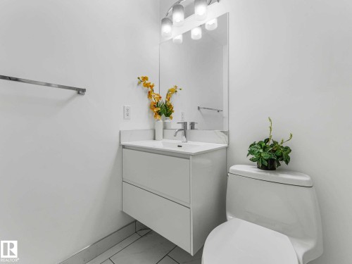 Bathroom featuring a wall-mounted vanity with integrated sink, chrome faucet, and mirrored medicine cabinet - 305 10504 99 Avenue, Edmonton, AB - Indoor Photo Showing Bathroom