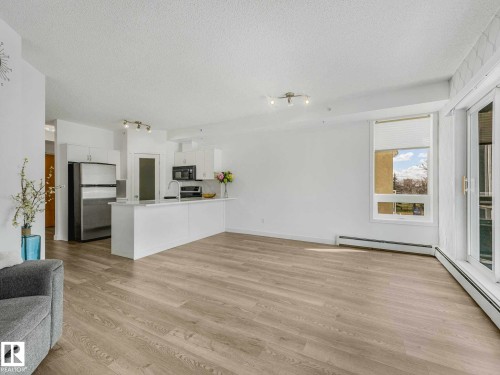 Open-concept living space featuring wood-finish flooring, white walls, and track lighting - 305 10504 99 Avenue, Edmonton, AB - Indoor