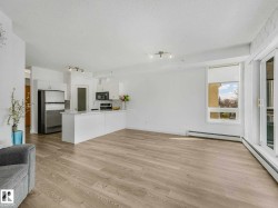 Open-concept living space featuring wood-finish flooring, white walls, and track lighting - 