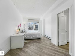 Bedroom featuring wood-finish flooring, a large window with blinds, and white baseboards - 