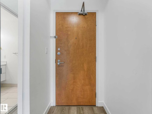 Natural wood-finish entry door with modern hardware - 305 10504 99 Avenue, Edmonton, AB - Indoor Photo Showing Other Room