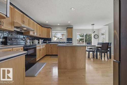 Kitchen featuring wood-finish cabinetry, black appliance suite, and light wood-finish flooring - 11551 14 Avenue, Edmonton, AB - Indoor Photo Showing Kitchen