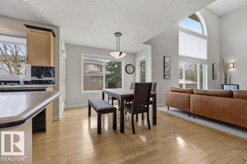 Open-concept living area featuring light wood-finish flooring, a kitchen island with a light-colored countertop, and a dining area with a modern pendant light - 11551 14 Avenue, Edmonton, AB - Indoor