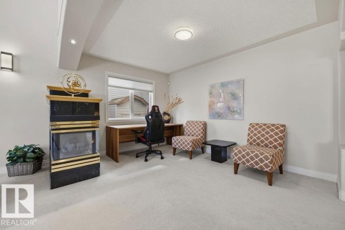 Dedicated room featuring a black and gold fireplace, a large window, recessed lighting, and light-colored carpeting - 11551 14 Avenue, Edmonton, AB - Indoor
