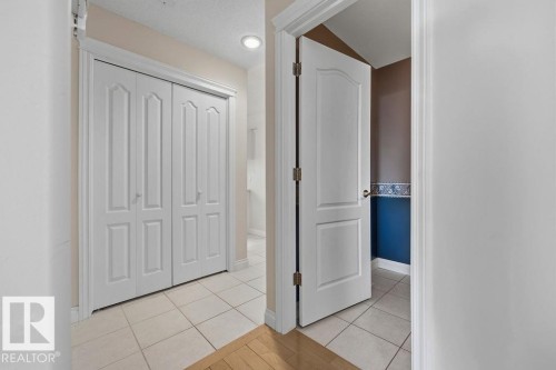 Hallway with light beige square tile flooring, white bi-fold closet doors, and recessed ceiling lighting - 11551 14 Avenue, Edmonton, AB - Indoor Photo Showing Other Room