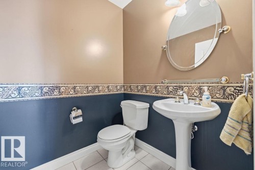 Pedestal sink with chrome fixtures, oval mirror, and overhead lighting - 11551 14 Avenue, Edmonton, AB - Indoor Photo Showing Bathroom