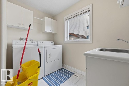 Dedicated laundry area featuring white cabinetry, a utility sink, and a window - 11551 14 Avenue, Edmonton, AB - Indoor Photo Showing Laundry Room