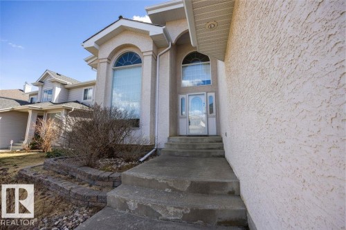 Stucco exterior with a prominent arched window feature, a full-lite entry door, and a multi-level concrete walkway - 11551 14 Avenue, Edmonton, AB - Outdoor