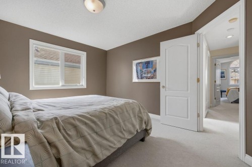 Carpeted bedroom featuring neutral wall tones, a textured ceiling, and a flush mount ceiling light fixture - 11551 14 Avenue, Edmonton, AB - Indoor Photo Showing Bedroom
