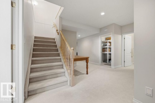 Carpeted staircase with light wood banister and spindles, recessed lighting, and a built-in storage niche with shelving - 11551 14 Avenue, Edmonton, AB - Indoor Photo Showing Other Room