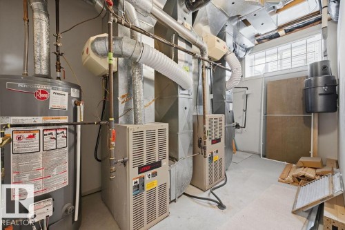 Utility room featuring a water heater, dual furnaces, extensive ductwork, and a window for natural light - 11551 14 Avenue, Edmonton, AB - Indoor Photo Showing Basement