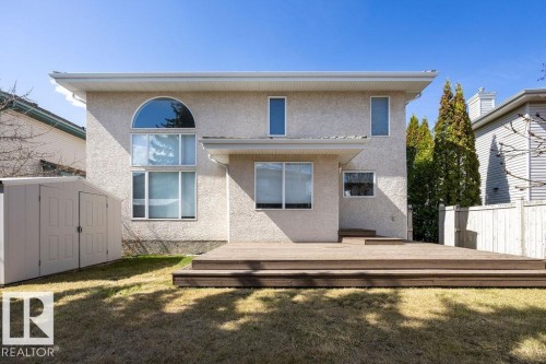 Rear exterior featuring stucco finish, a multi-level wood deck, an arched window, multiple rectangular windows, and a storage shed - 11551 14 Avenue, Edmonton, AB - Outdoor