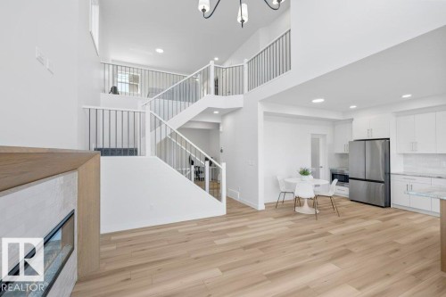 Two-story living area featuring wood-finish flooring and a central staircase with white railings - 19110 20A Avenue, Edmonton, AB - Indoor