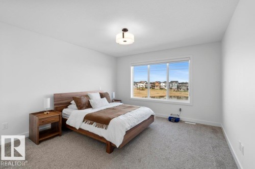 Spacious room featuring broadloom carpeting, a large picture window, and a contemporary ceiling light fixture - 19110 20A Avenue, Edmonton, AB - Indoor Photo Showing Bedroom