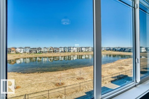 Sliding glass door system overlooking a body of water, with houses reflected on the surface - 19110 20A Avenue, Edmonton, AB -  With Body Of Water With View