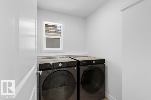 Dedicated laundry area featuring a white-framed window, light wall paint, and baseboard trim - 19110 20A Avenue, Edmonton, AB - Indoor Photo Showing Laundry Room