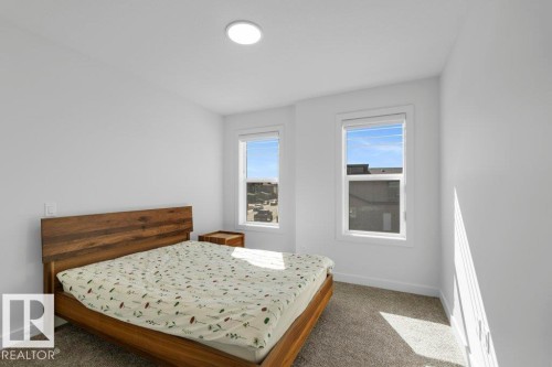 Light-filled room featuring two windows, neutral carpeting, and a recessed ceiling light fixture - 19110 20A Avenue, Edmonton, AB - Indoor Photo Showing Bedroom