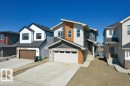 Modern exterior showcasing multi-tone siding, stone accents, and a dual-panel garage door - 19110 20A Avenue, Edmonton, AB  - Outdoor With Facade 