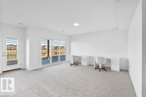 Carpeted room with a sliding glass door and an additional glass-paneled door opening to an outdoor patio - 19110 20A Avenue, Edmonton, AB - Indoor