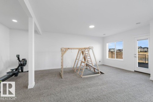 Spacious room featuring light gray carpeting, recessed lighting, and a white interior column - 19110 20A Avenue, Edmonton, AB - Indoor
