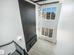 Two-story living area featuring a full-height tiled accent wall with an integrated linear fireplace - 