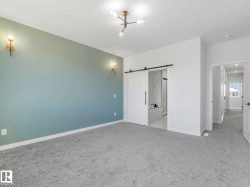 Room featuring light blue accent wall, neutral carpet flooring, modern ceiling light fixture, and two wall sconces - 