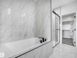 White tiled bathroom featuring a built-in tub with matte black fixtures, a glass-enclosed shower, and a doorway opening to a closet with built-in shelving and carpeted flooring - 