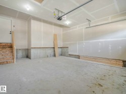 Spacious unfinished garage featuring a concrete floor, high ceilings, and a built-in staircase for interior access - 