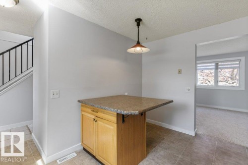 Kitchen island featuring wood cabinetry and a speckled countertop - 3736 12 Avenue, Edmonton, AB - Indoor Photo Showing Other Room