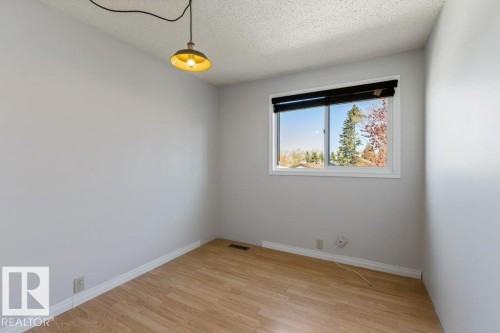 Bright interior room featuring light wood-finish flooring, neutral gray wall paint, and white baseboards - 3736 12 Avenue, Edmonton, AB - Indoor Photo Showing Other Room