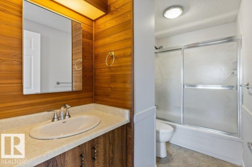 Bathroom featuring a wood-panel accent wall and a vanity with an integrated sink - 3736 12 Avenue, Edmonton, AB - Indoor Photo Showing Bathroom